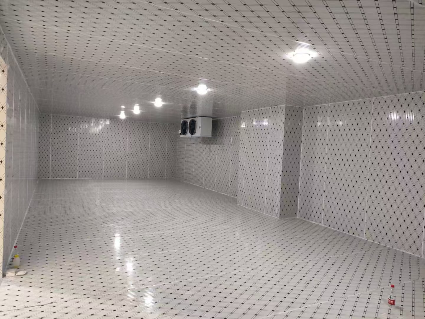 Reflective patterned surfaces cover the walls, ceiling and floor. Ceiling lights and a wall-mounted air cooler are visible in the open storage space.